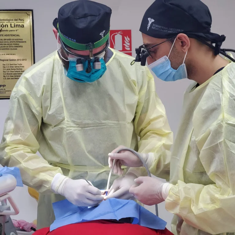 Two dental surgeons wearing surgical loupes and yellow gowns performing an All-on-X dental implant procedure on a patient in a dental clinic